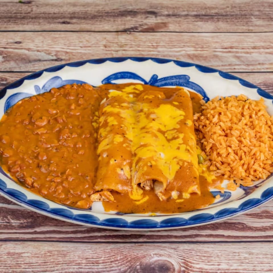 Chicken enchiladas with red sauce and melted cheese, served with refried beans and Spanish rice.