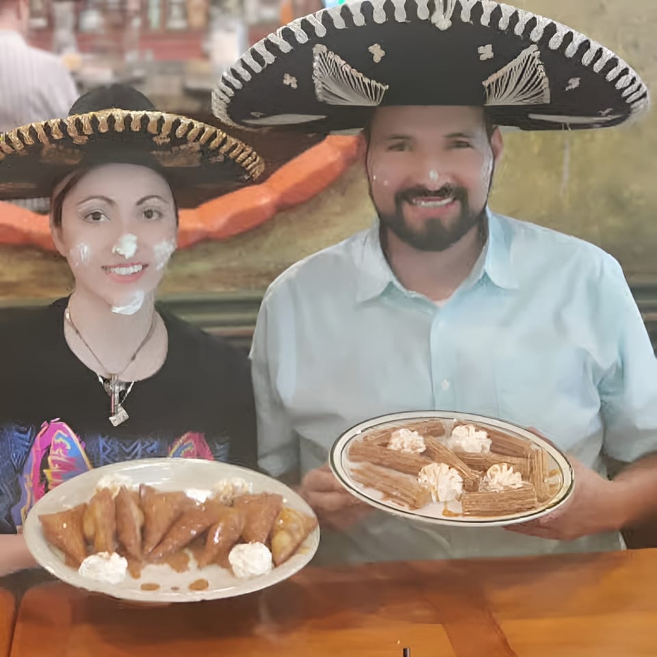 Two people in sombreros with whipped cream on their faces, holding plates of desserts.
